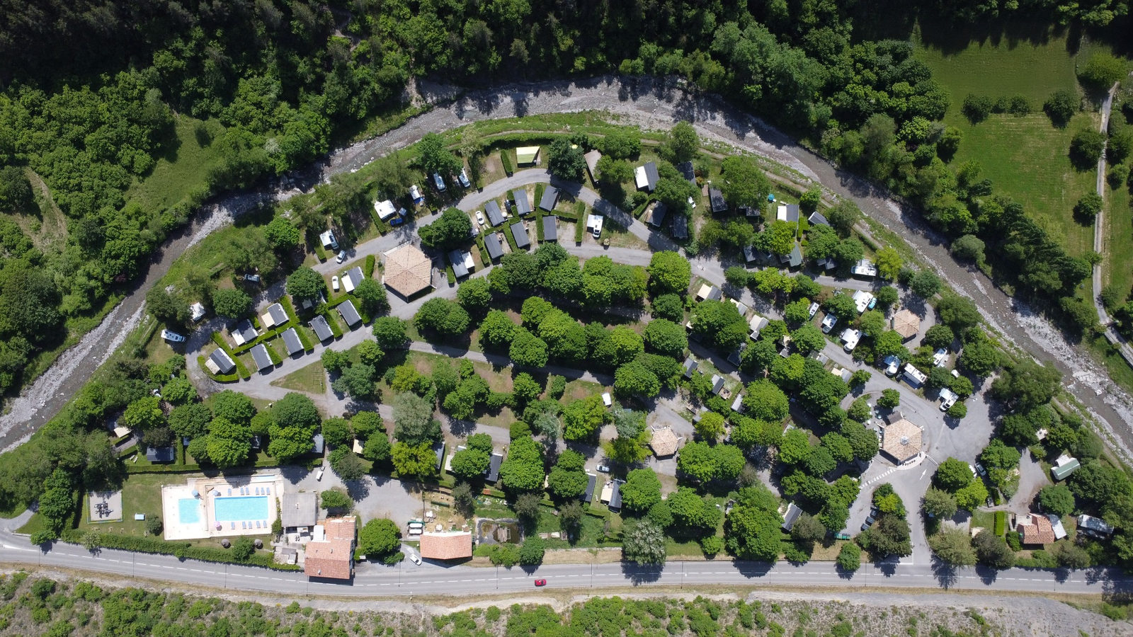 Vue aérienne du camping : hébergements, piscine, voies internes et rivière