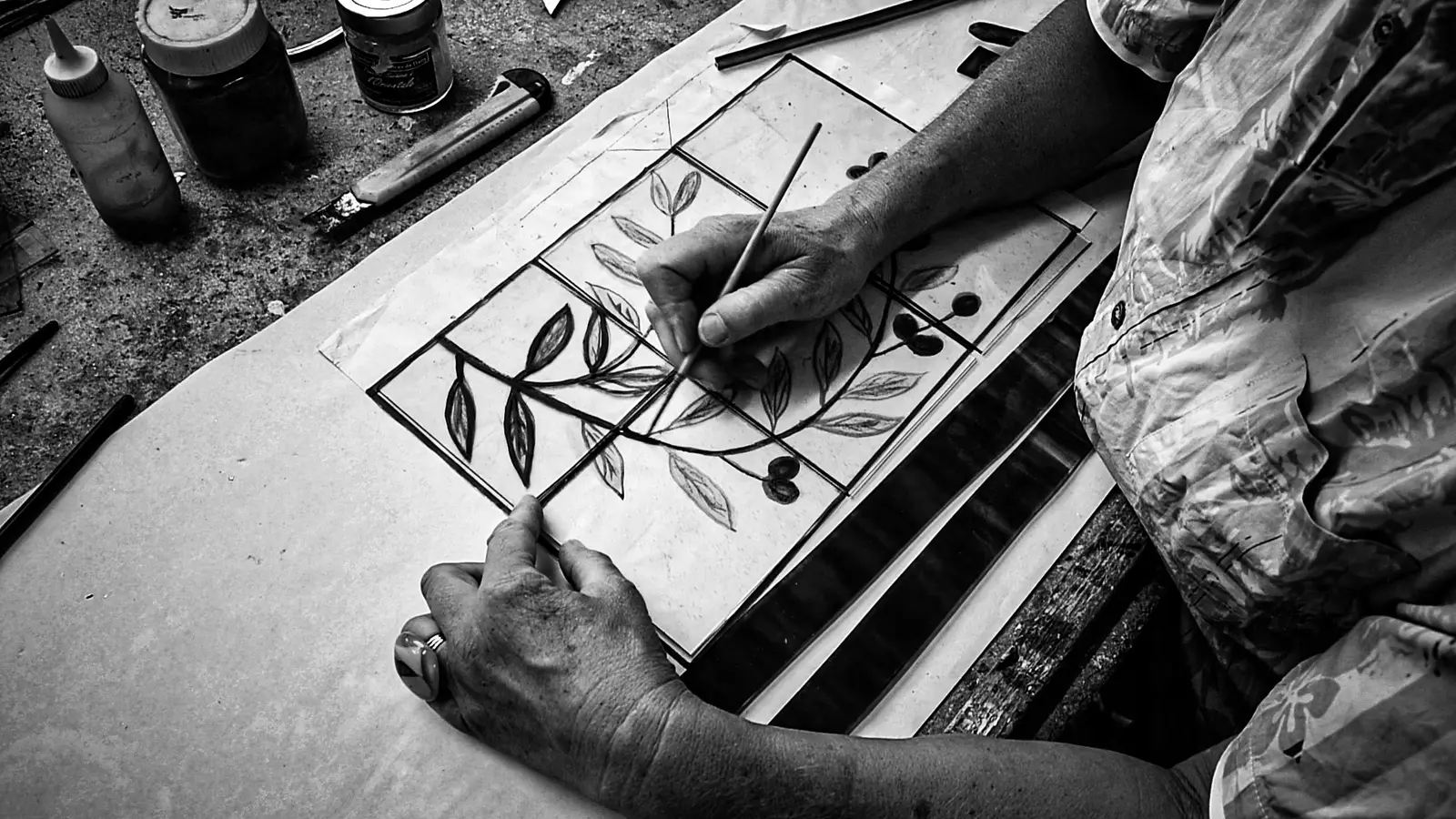 Main d’un artisan dessinant un motif végétal sur une pièce